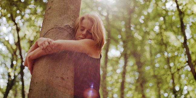 Young woman hugging tree, eyes closed